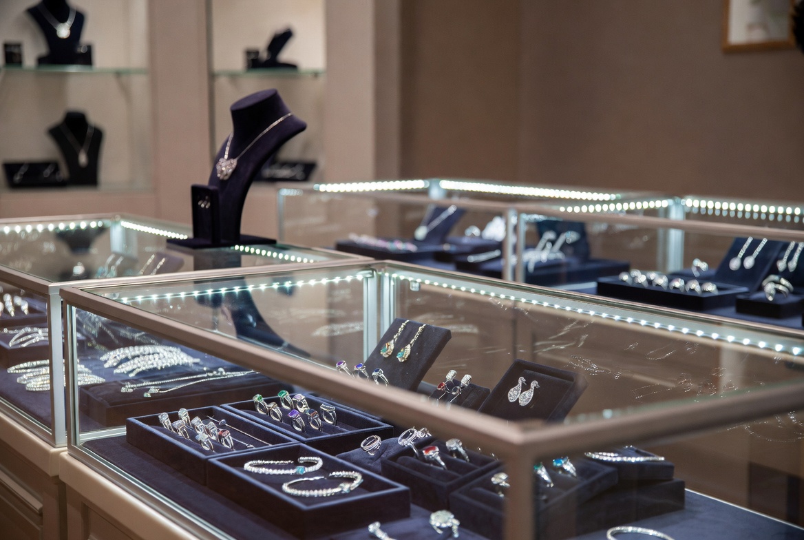 Elegant consignment jewelry retail display cases with curated premium consigned pieces including diamond rings, gemstone jewelry, and estate items