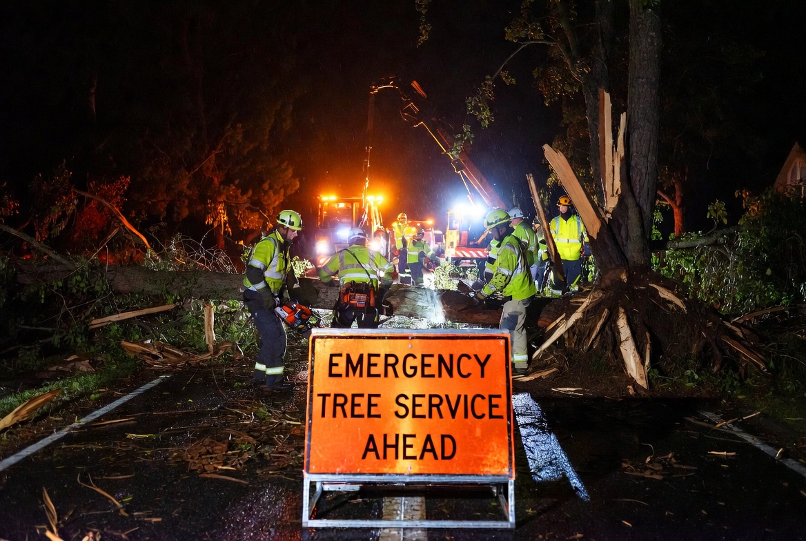 Orange emergency tree service ahead sign at storm damage work site - Kelly Insurance Group