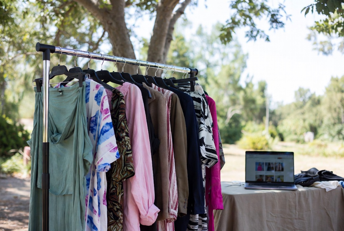 Mobile fashion e-commerce influencer photo shoot on location with rolling clothing rack and laptop for live edit and post production