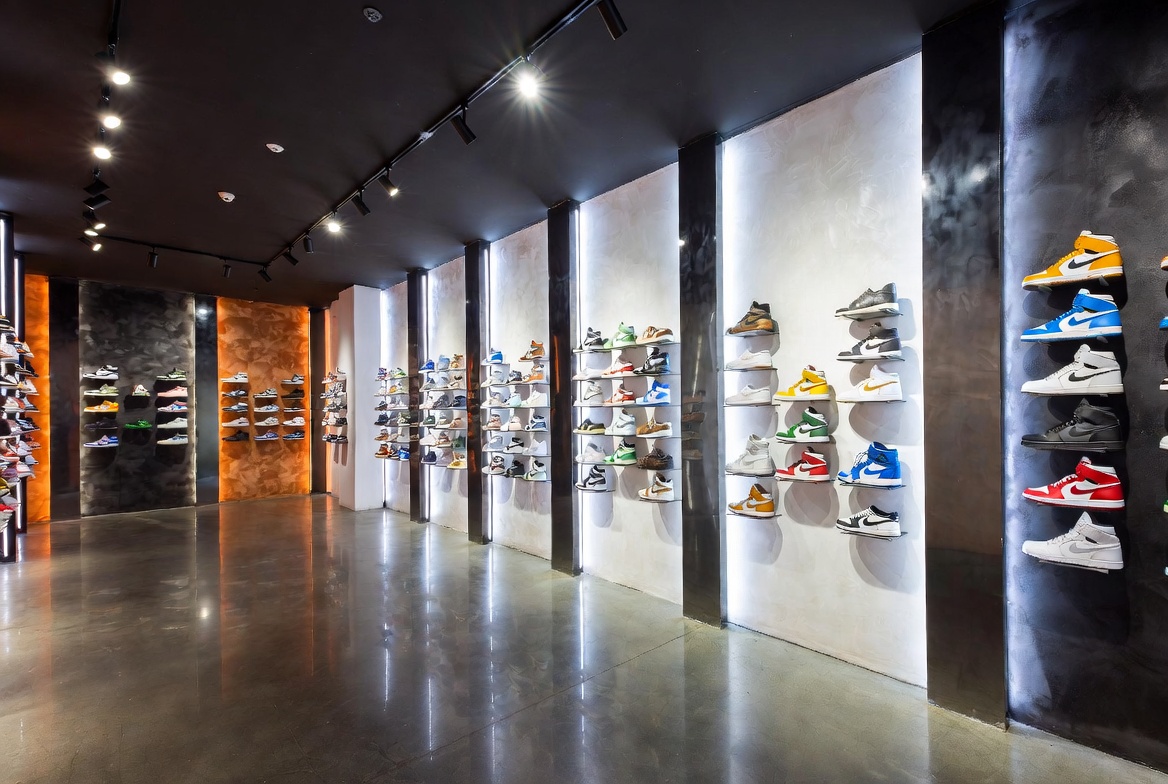 Sleek luxury sneaker retail store interior with floating shelves displaying limited edition releases and grail tier sneakers under directional lighting