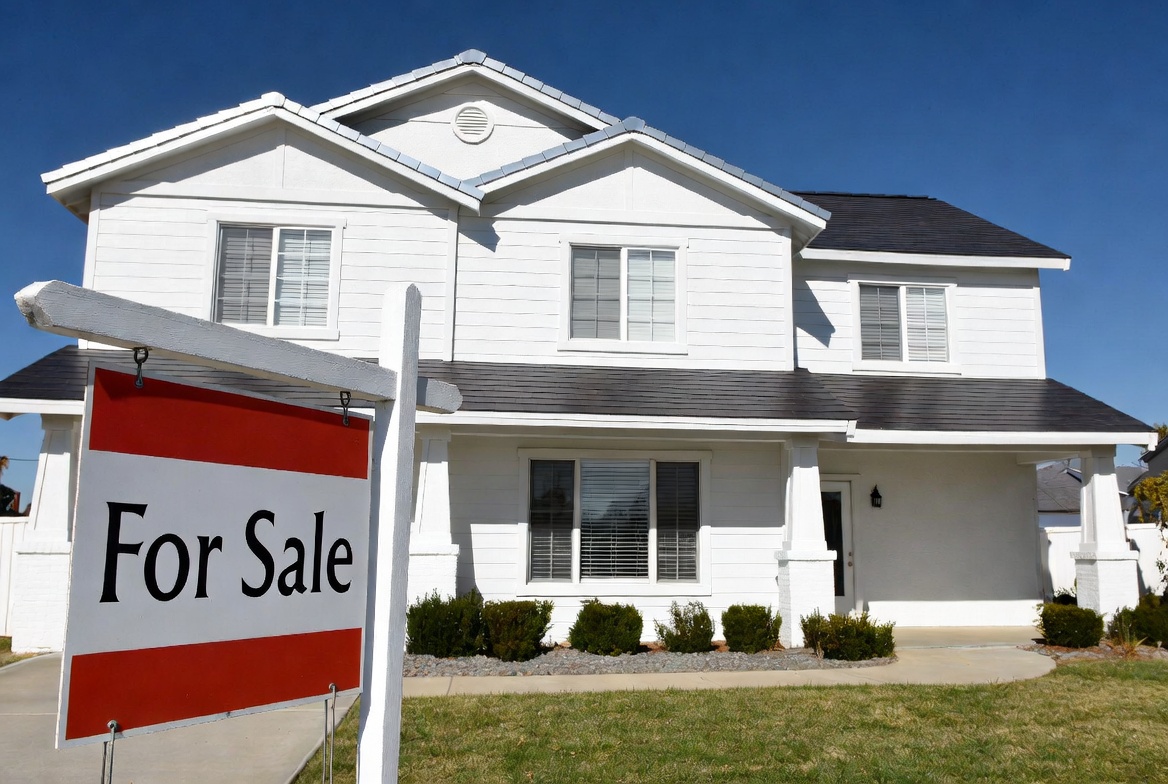 Vacant two-story home with a prominent for sale sign in the front yard representing the kind of empty residential property that needs vacant home insurance coverage