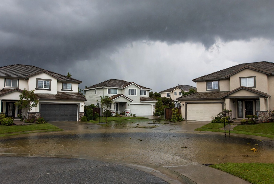 Residential homes submerged in floodwater — flood losses are excluded from standard homeowners and commercial property policies